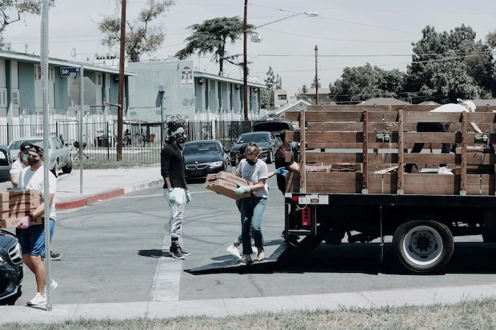 Image of people unloading boxes from a truck (By Joel Muniz on Unsplash) Alt Text